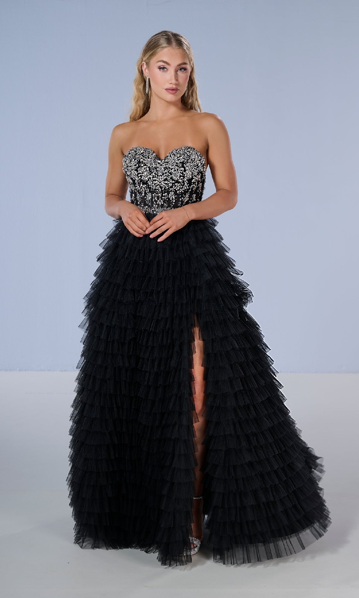 Woman models the Tiffany 16220 long prom dress, showcasing its beaded sweetheart bodice and tiered ruffle skirt, against a plain light background.